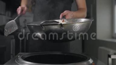 厨师用热锅炒菜，慢动作，煮亚洲面条，在热锅里搅拌